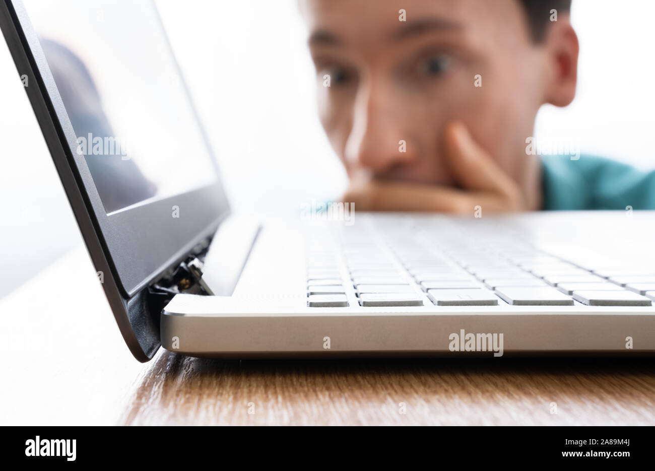 Man Looking At Damaged Laptop Computer With Broken Screen Attachment