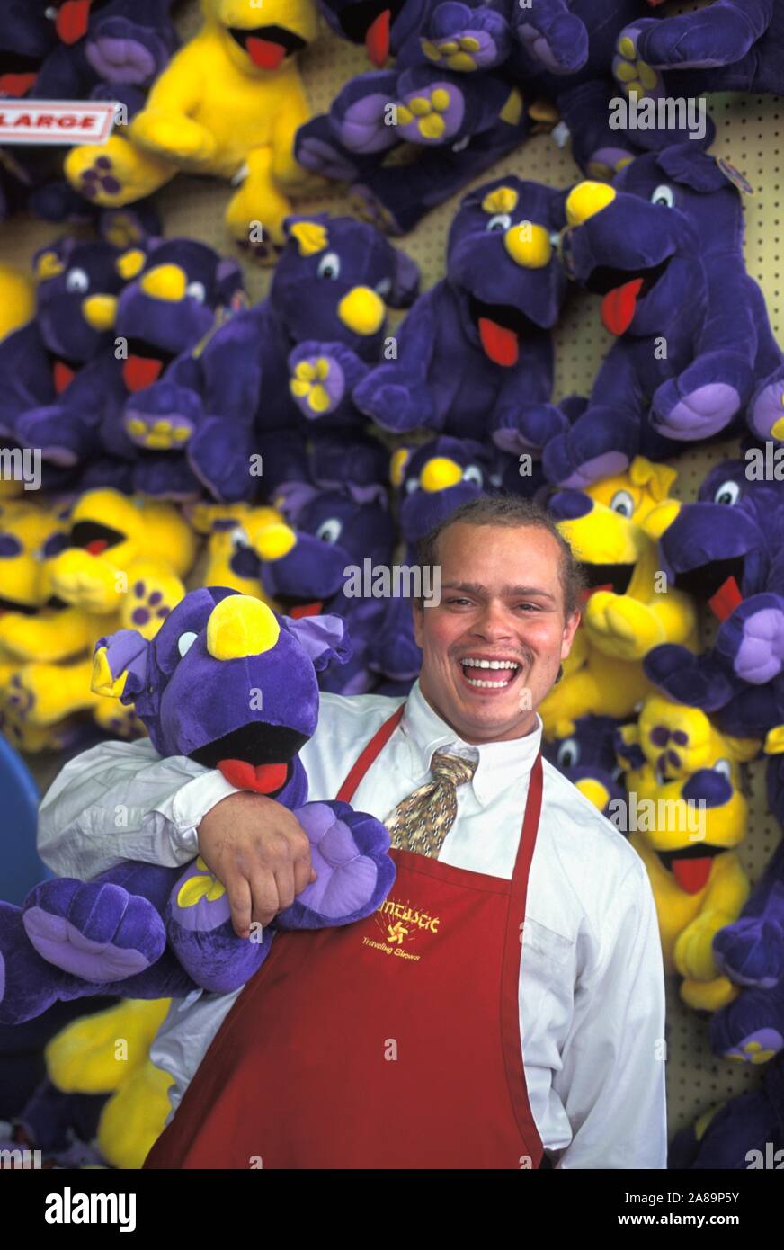 A portrait of a Caucasian carnival worker in front of a bevy of stuffed prizes Stock Photo