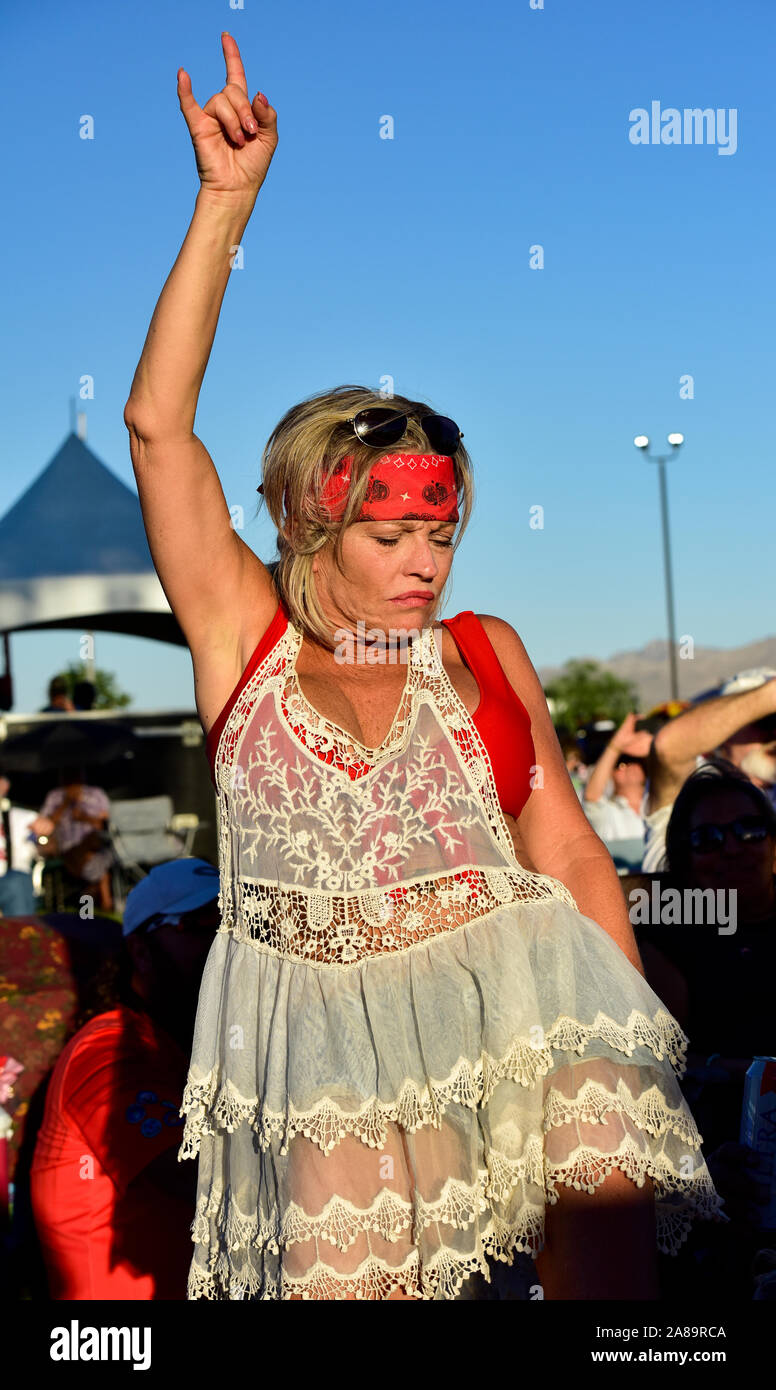 Concert goer dancing to music in the audience in front of stage Stock Photo