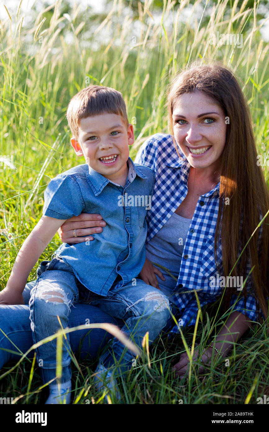 Mom and little son lie on the grass in the woods Stock Photo
