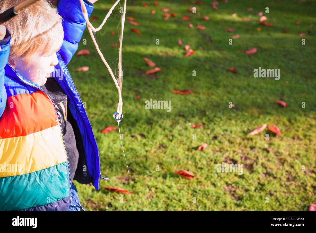 Child playing outside in a garden during day time with bubbles he is happy and running Stock Photo