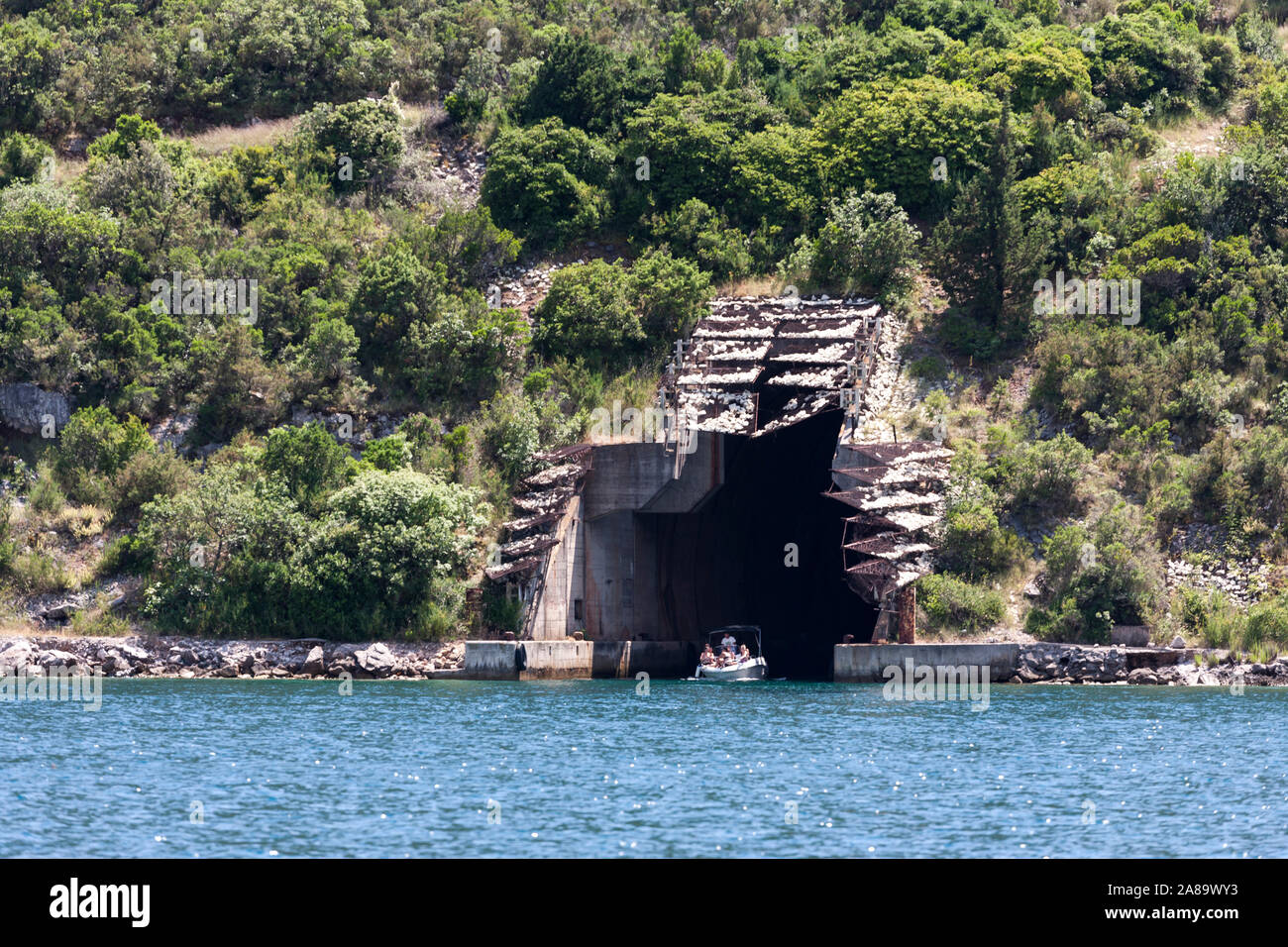 Small boat emerging from a World War II-era submarine pen, Luštica peninsula, Rose, Montenegro Stock Photo