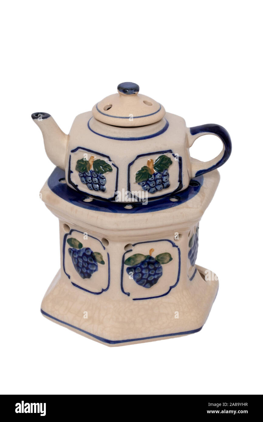 Close-up of a vintage teapot with warmer made of ceramic pottery  with a colorful blue pattern isolated on a white background. The tea on the stove is Stock Photo