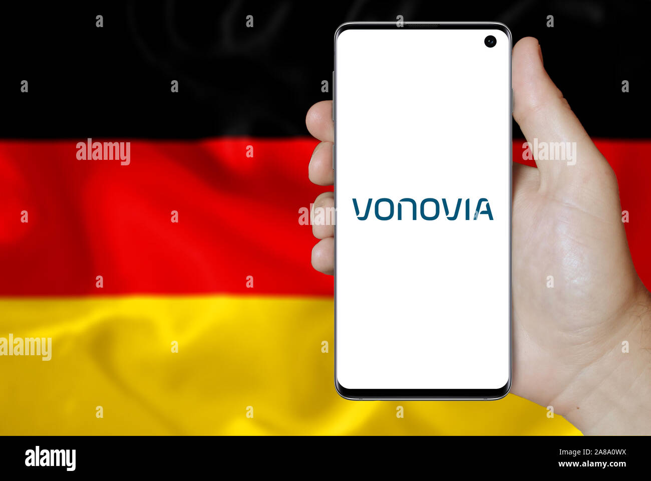 Logo of public company Vonovia displayed on a smartphone. Flag of