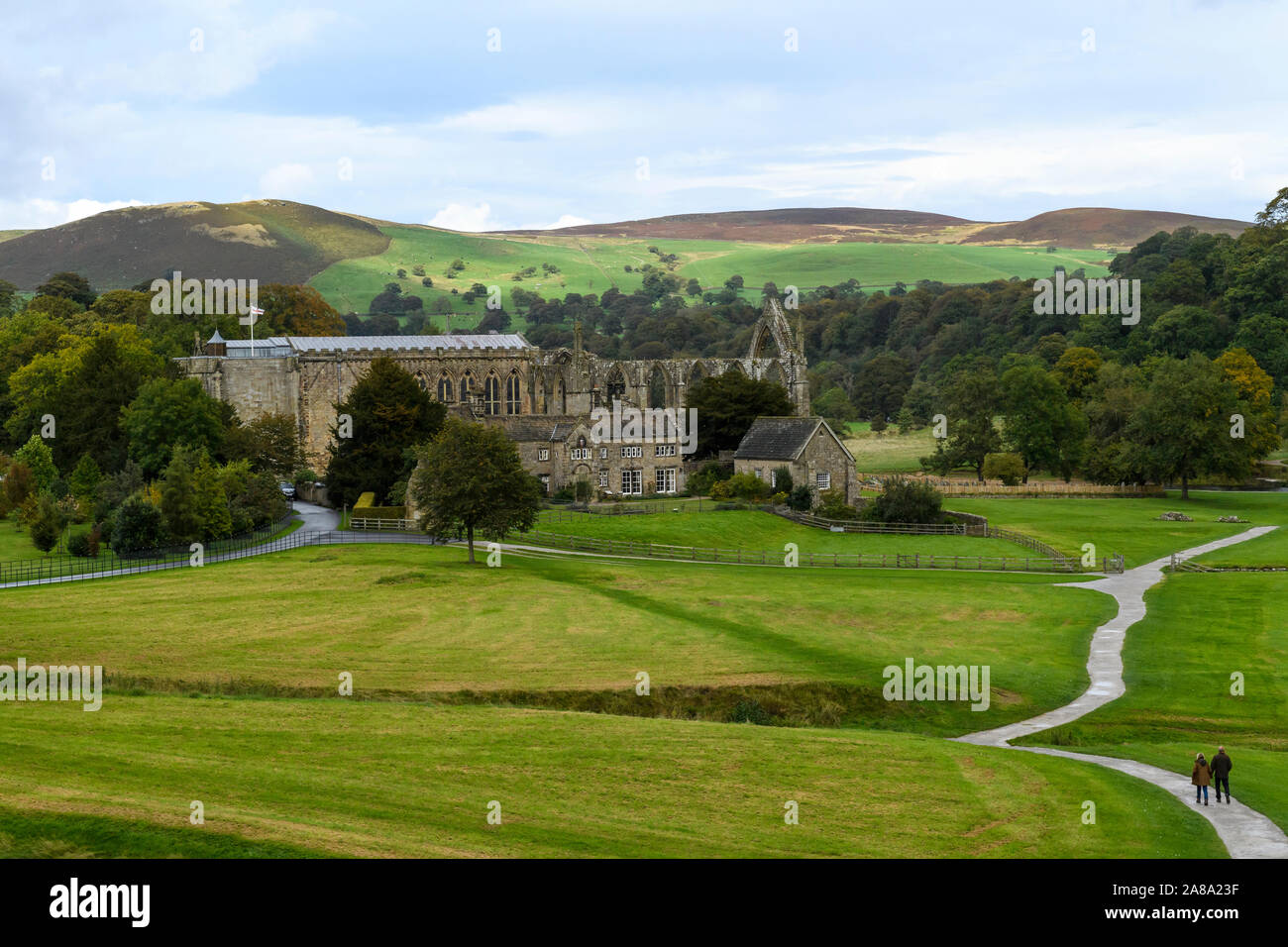 Ancient picturesque monastic Bolton Abbey ruins, Priory Church, Old Rectory & people on winding path - scenic rural view, Yorkshire Dales, England, UK Stock Photo