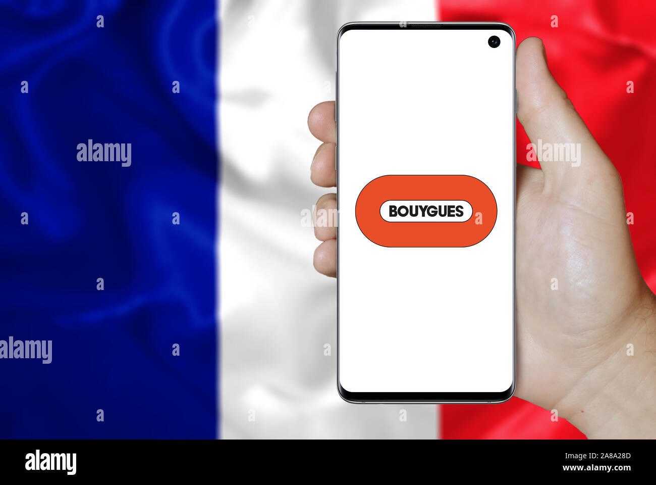 Logo of public company Bouygues displayed on a smartphone. Flag of France background. Credit: PIXDUCE Stock Photo
