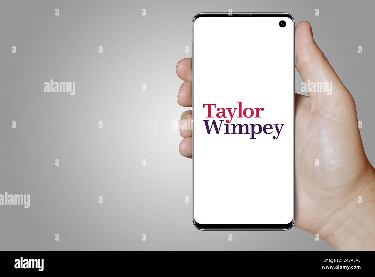 Logo of public company Taylor Wimpey displayed on a smartphone. Grey background. Credit: PIXDUCE Stock Photo