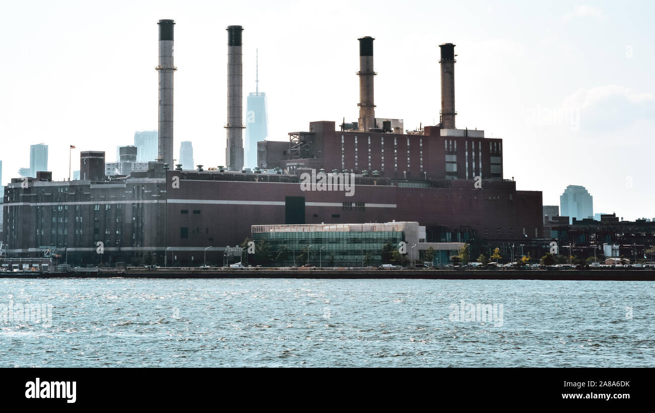 Office, apartments and industrial chimneys buildings in the skyline at sunset, from Hudson river. Pollution and industry concept. Manhattan, New York Stock Photo