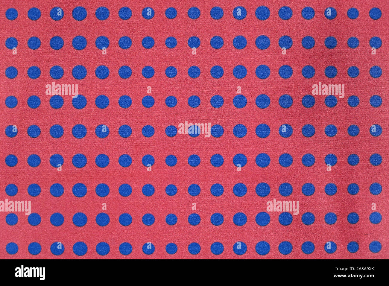 Blue dots on red background grainy wall pattern Stock Photo