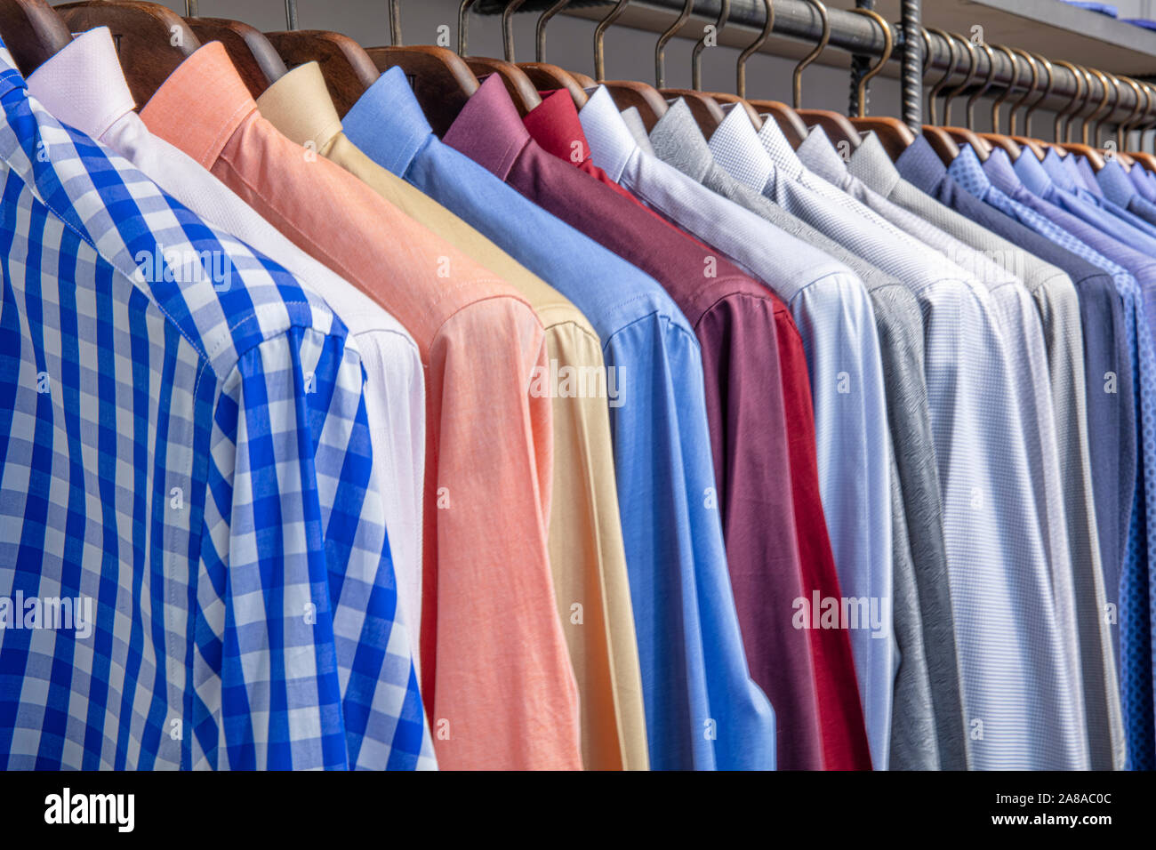 Men shirts on hanger for sale in shop. Male wear on wooden hanger. Official wear for men in department store. Office apparel for autumn or winter. Sal Stock Photo