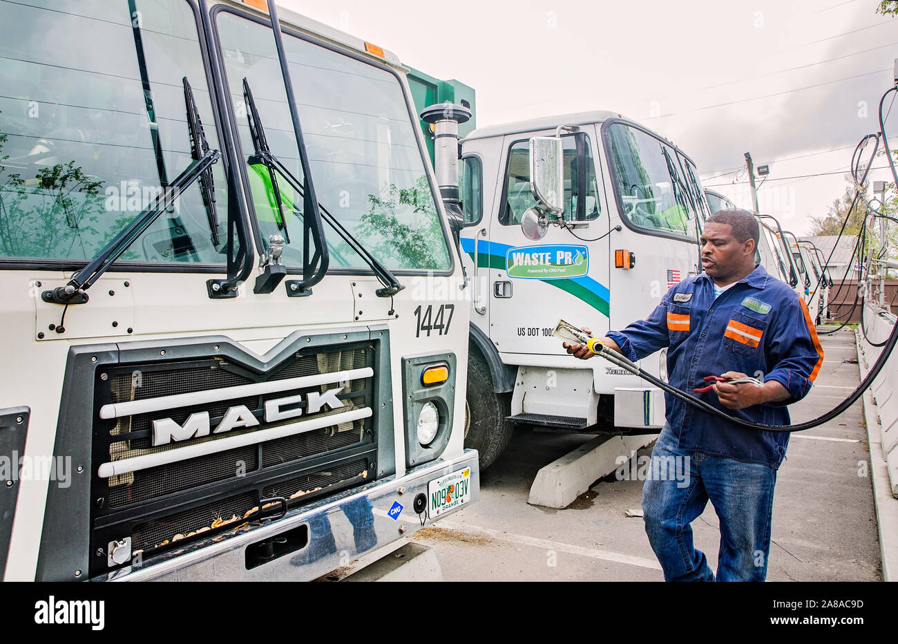 A diesel mechanic attaches a CNG-powered (compressed natural gas) Mack Truck to a time-fill station at Waste Pro in Jacksonville, Florida. Stock Photo