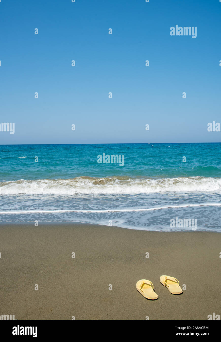 Yellow sandals , flip flops, on a golden sandy beach welcoming summer ...