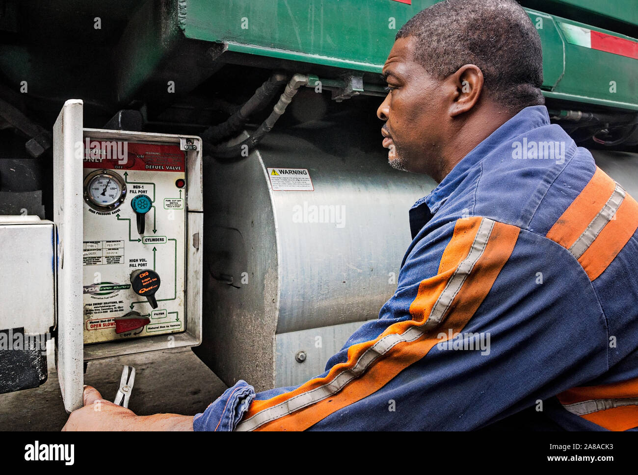 A diesel mechanic checks the control panel of a CNG-powered (compressed natural gas) Mack Truck at Waste Pro in Jacksonville, Florida. Stock Photo