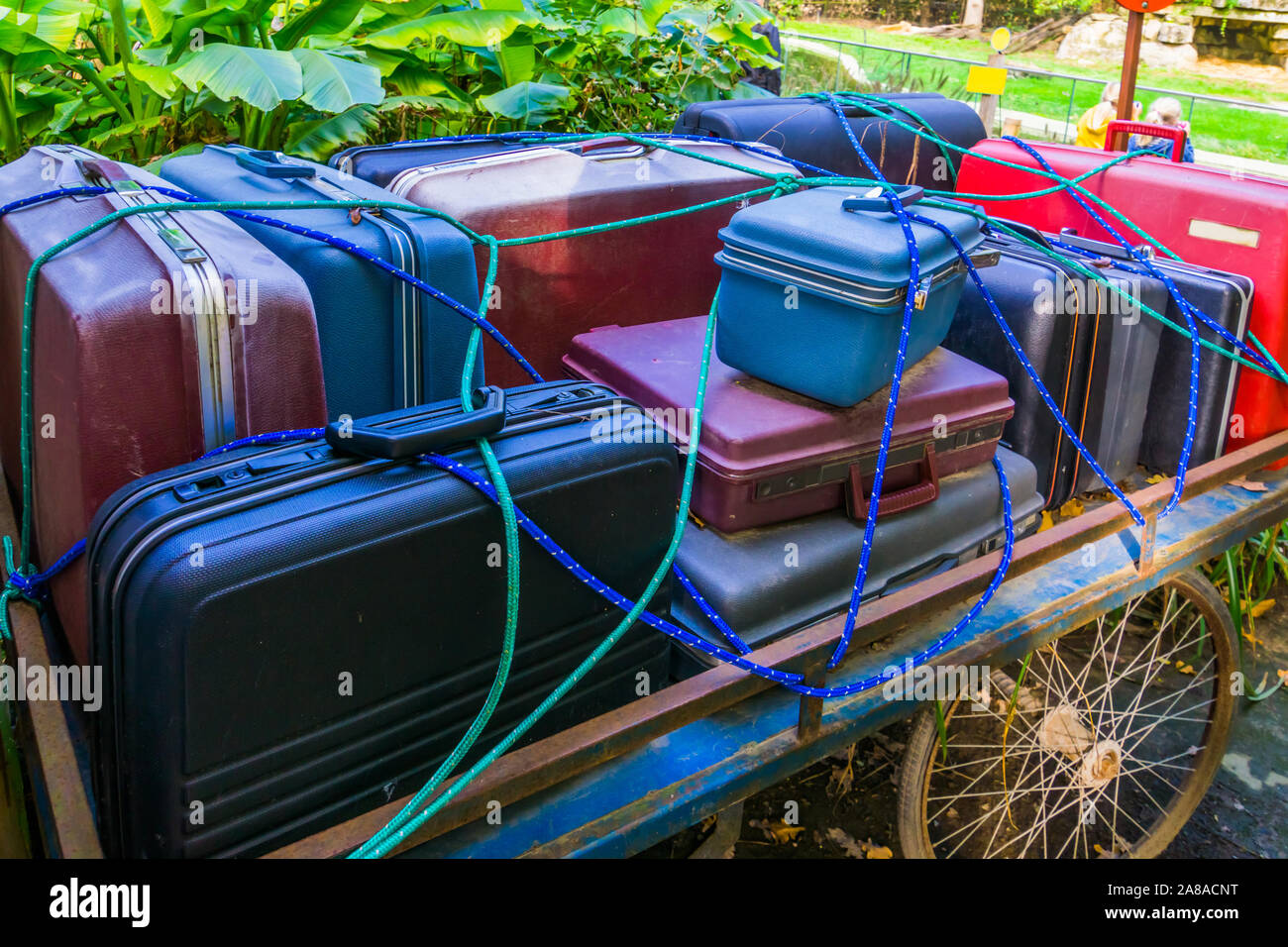 old luggage cart filled with suitcases that are secured by a rope