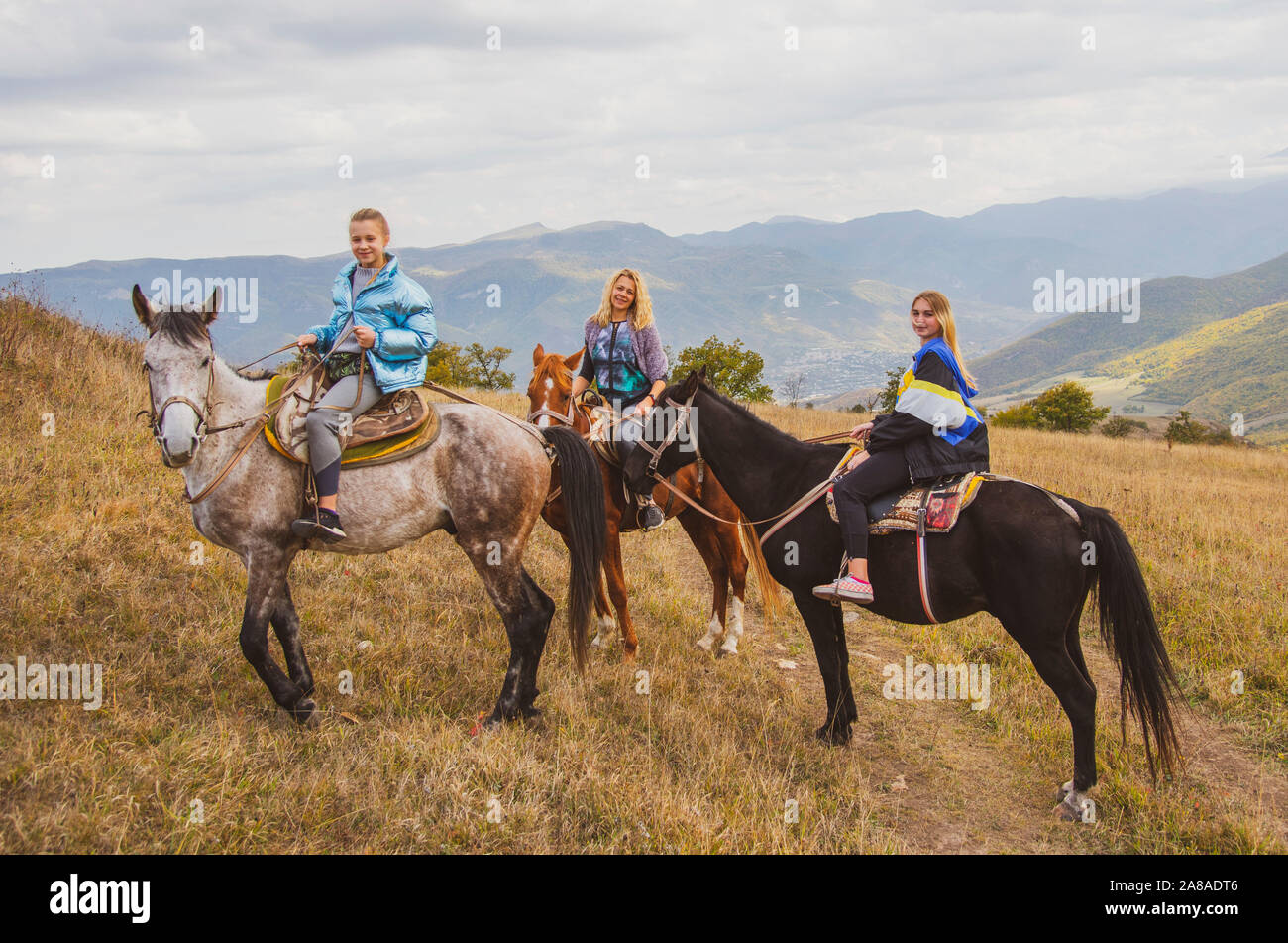 Three girls on horseback on the background of the mountain autumn ...