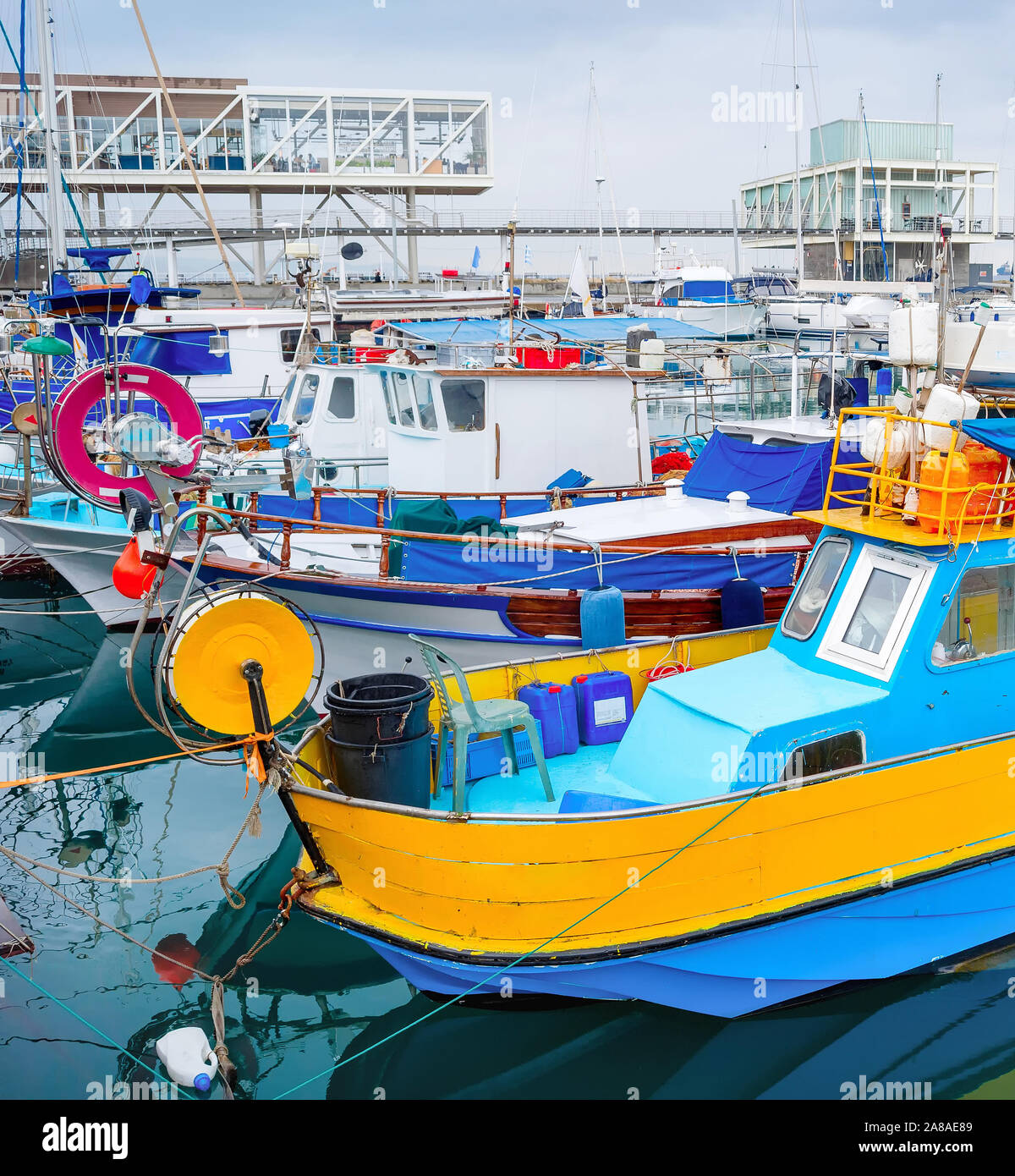Colorful fishing boats moored in Limassol marina with restaurants on pier, Cyprus Stock Photo