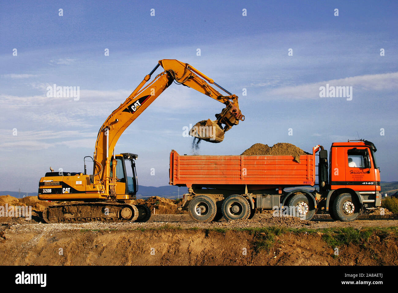 Bagger und LKW bei Erdarbeiten, Bagger belädt LKW mit abgetragener Erde, Stock Photo