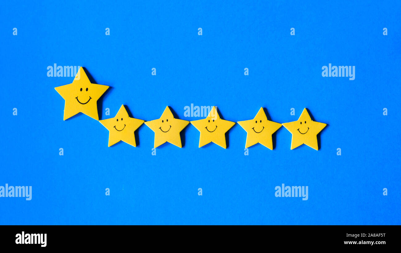 leadership and teamwork concept, big yellow star leads small stars on a blue background Stock Photo
