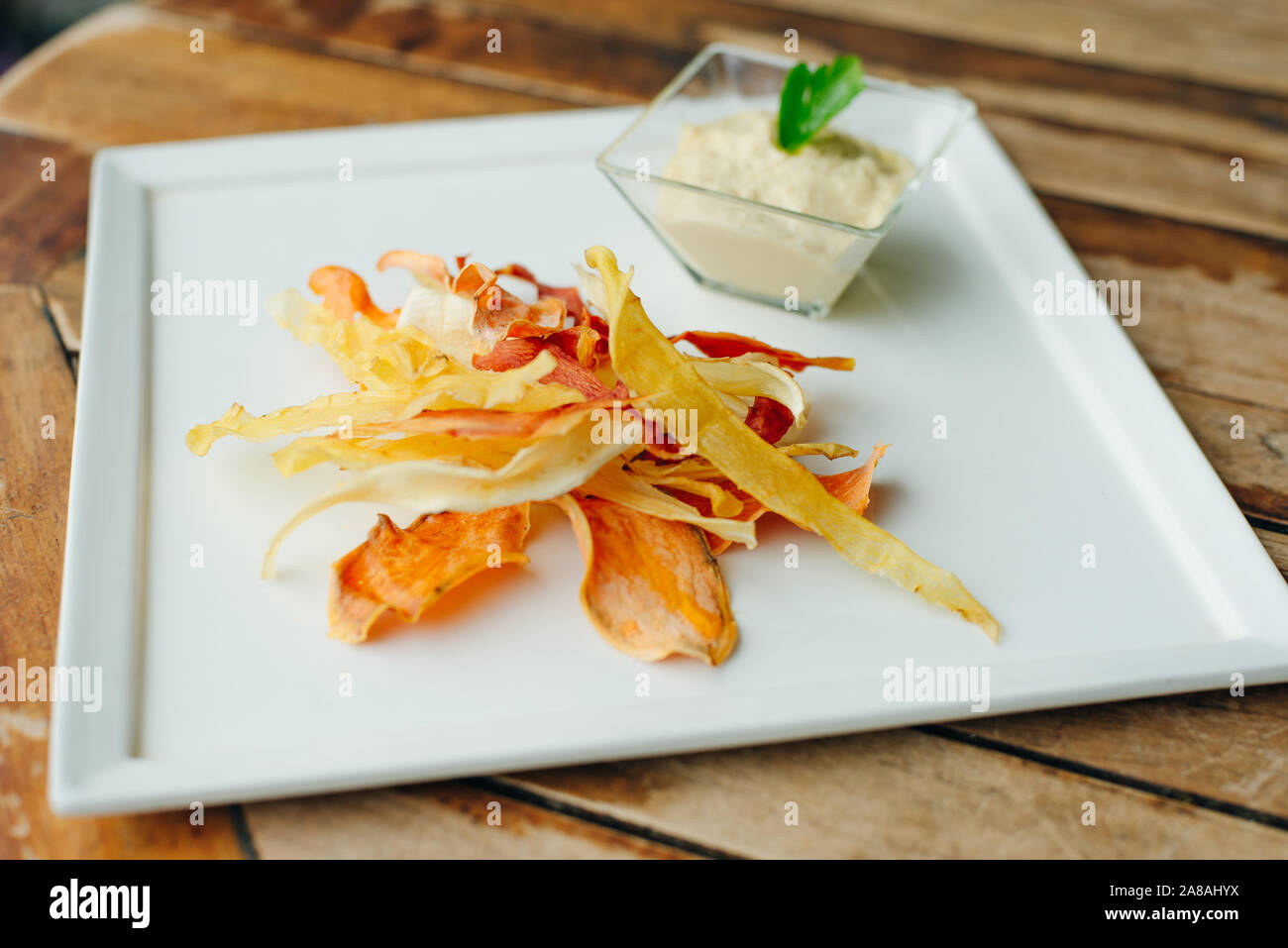 hummus with root vegetable color chips in restaurant Stock Photo