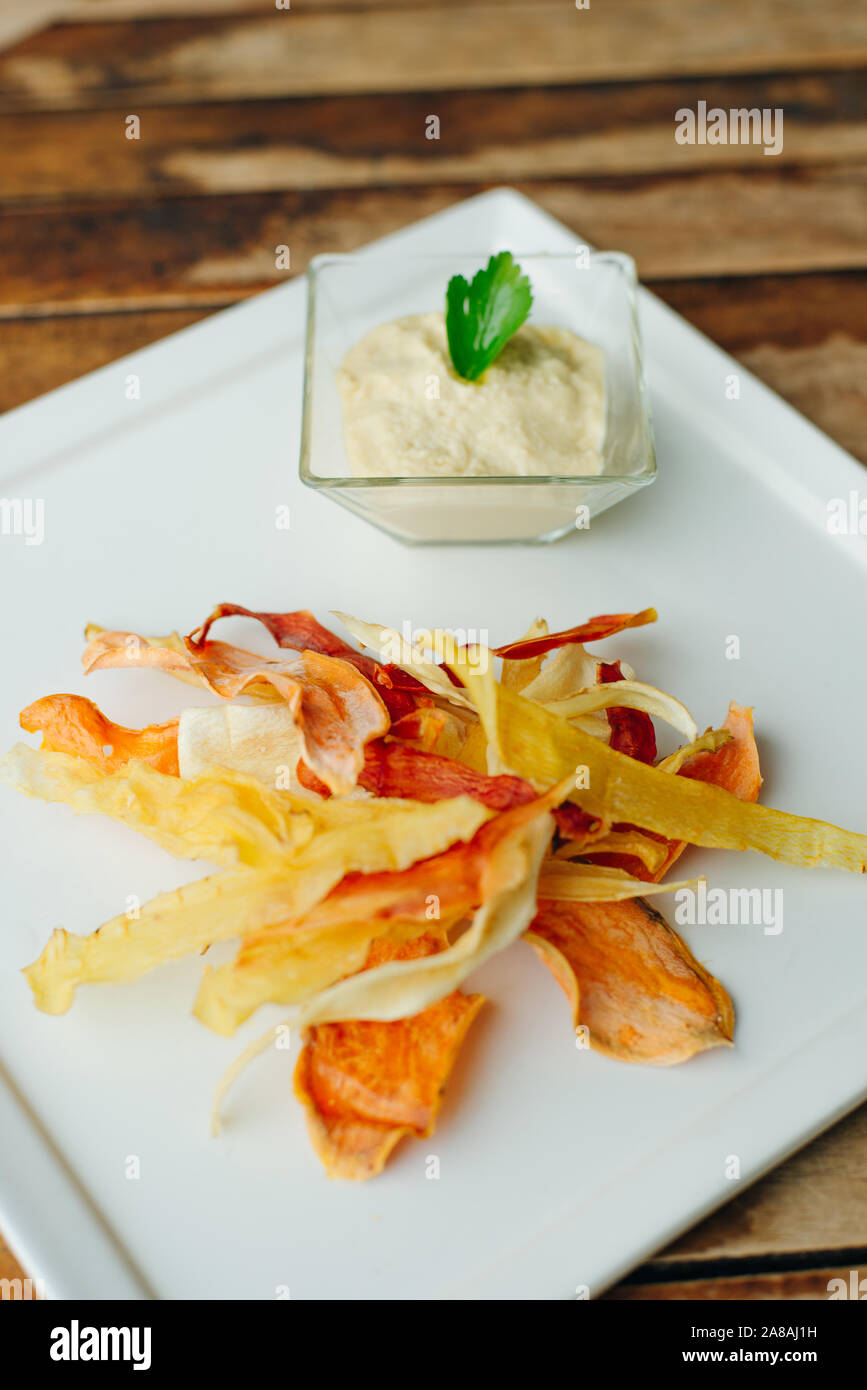 hummus with root vegetable color chips in restaurant Stock Photo