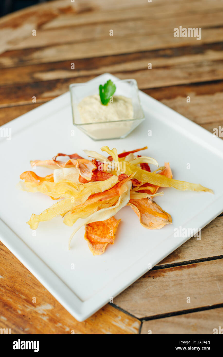hummus with root vegetable color chips in restaurant Stock Photo
