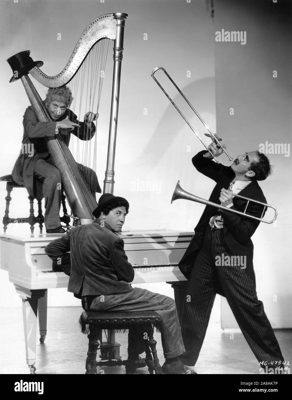 HARPO MARX on harp CHICO MARX on piano and GROUCHO MARX on trombone THE MARX BROTHERS Portrait by Clarence Sinclair Bull for A NIGHT AT THE OPERA 1935 director Sam Wood screenplay George S. Kaufman and Morrie Ryskind producer Irving Thalberg Metro Goldwyn Mayer Stock Photo