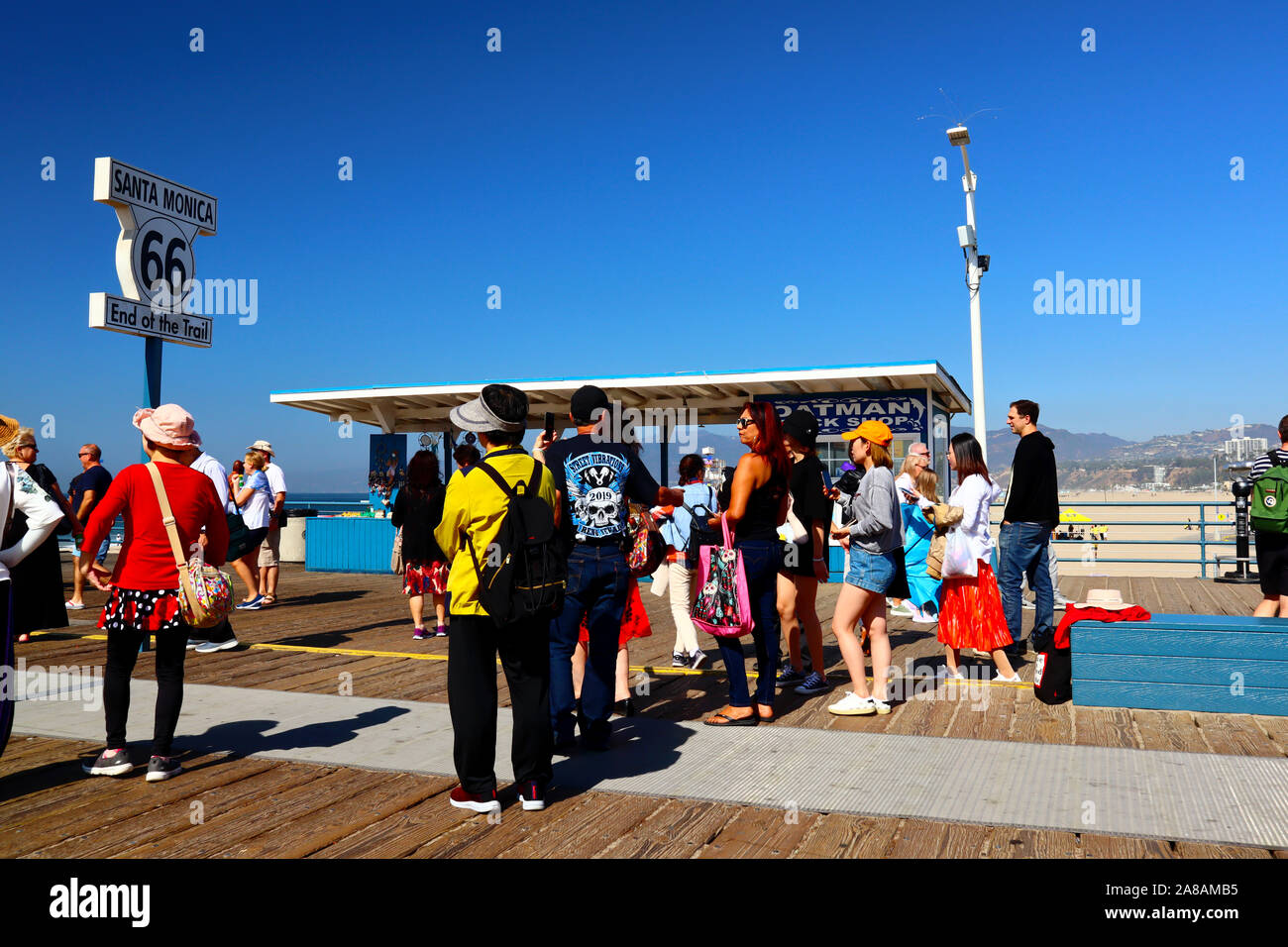 Tourists taking pictures of the sign Route 66 End of the Trail, located on the Pier of Santa