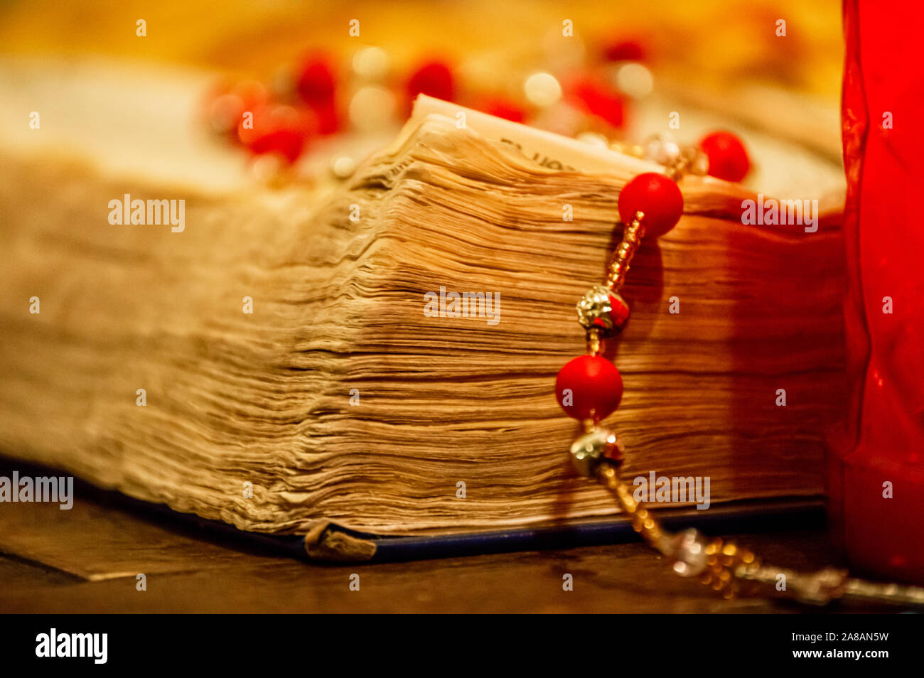 Corner pages of an old worn Bible book and a Catholic rosary beads. Stock Photo