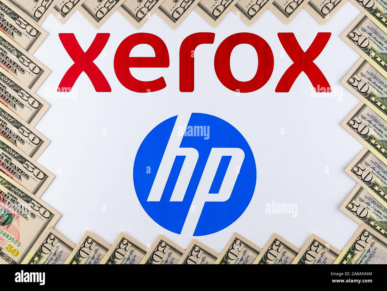 XEROX and HP logos seen on the paper brochure and dollar bills around. Concept image for the news about XEROX bid to buy HP. Stock Photo