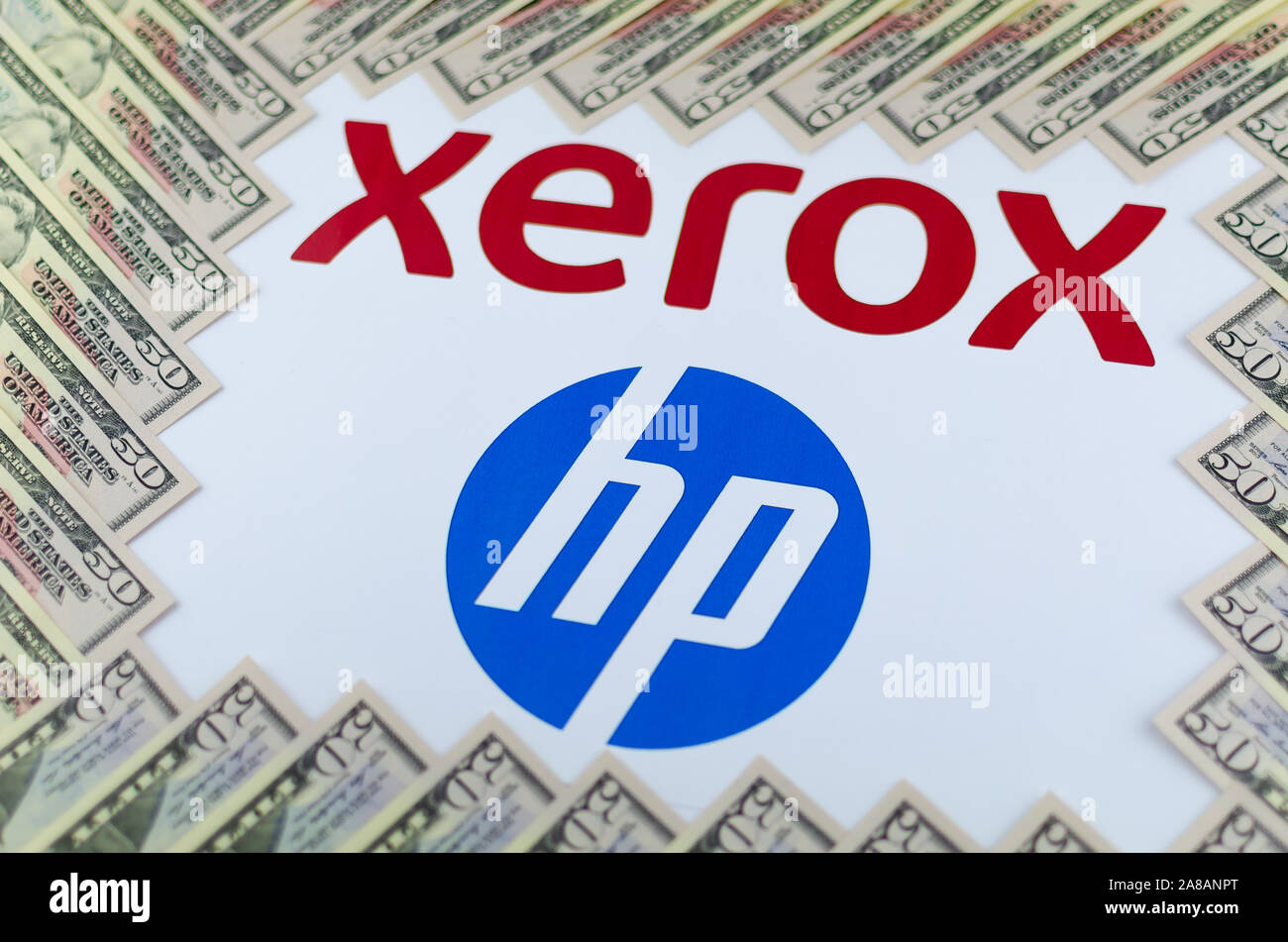 XEROX and HP logos seen on the paper brochure and dollar bills around. Concept image for the news about XEROX bid to buy HP. Stock Photo