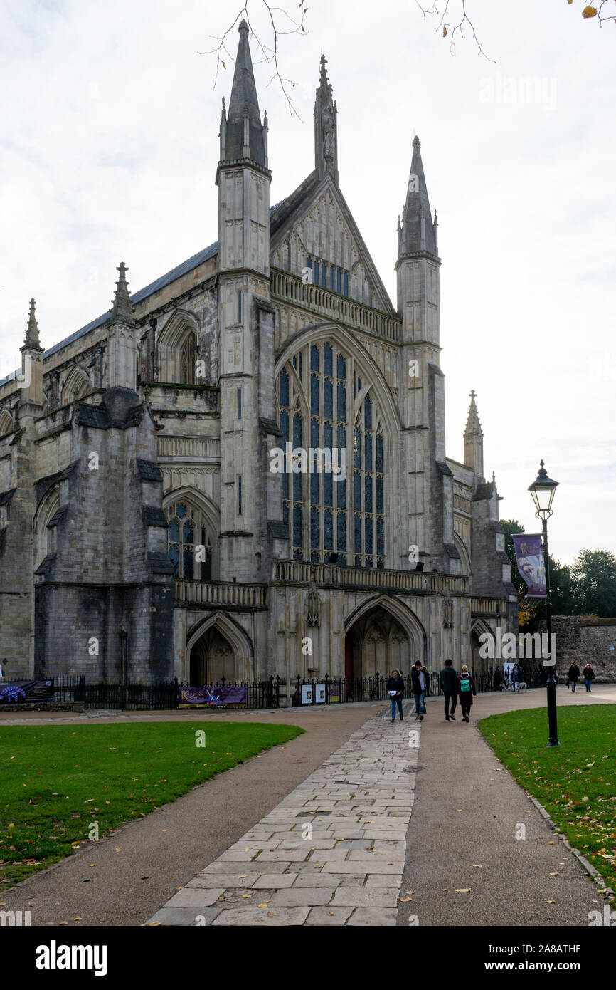 Winchester cathedral with Tourists walking past, Winchester, Hampshire, UK Stock Photo