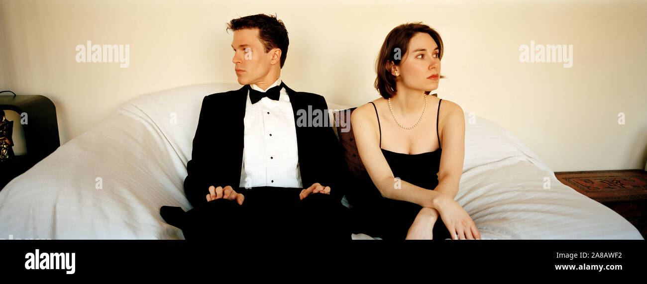 Young Man And Woman Couple Sitting On A Couch In Formal Evening Wear Before A Date Stock Photo