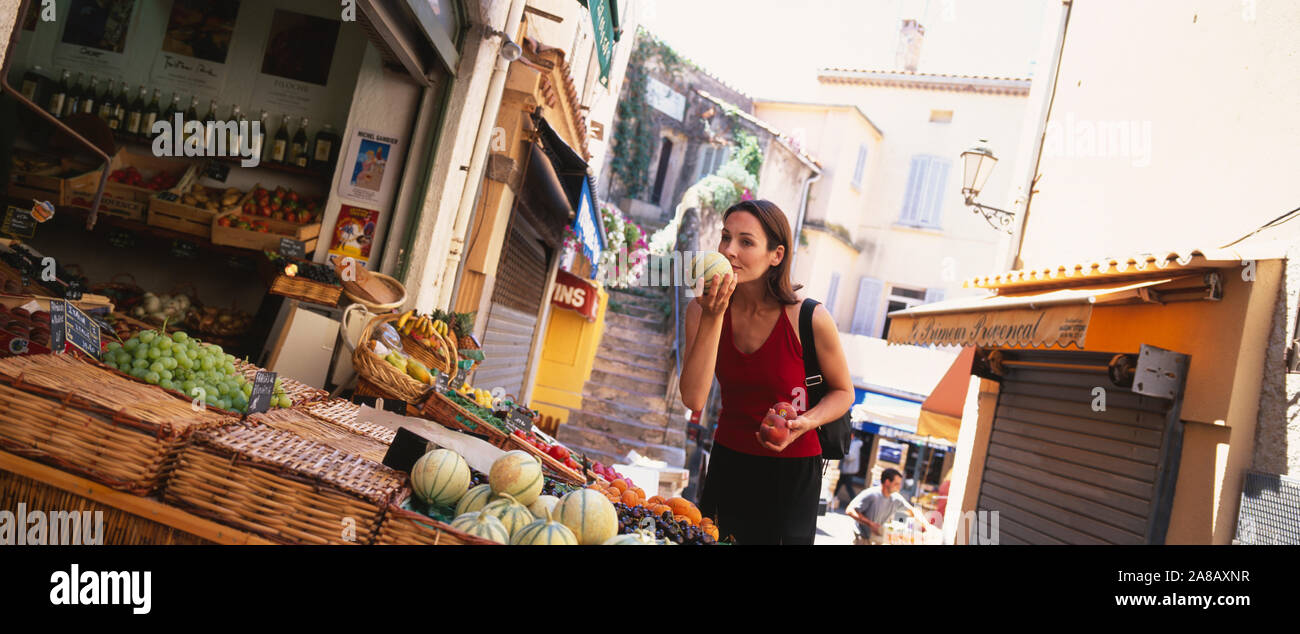 Young woman smelling a melon in a market, St. Tropez, France Stock