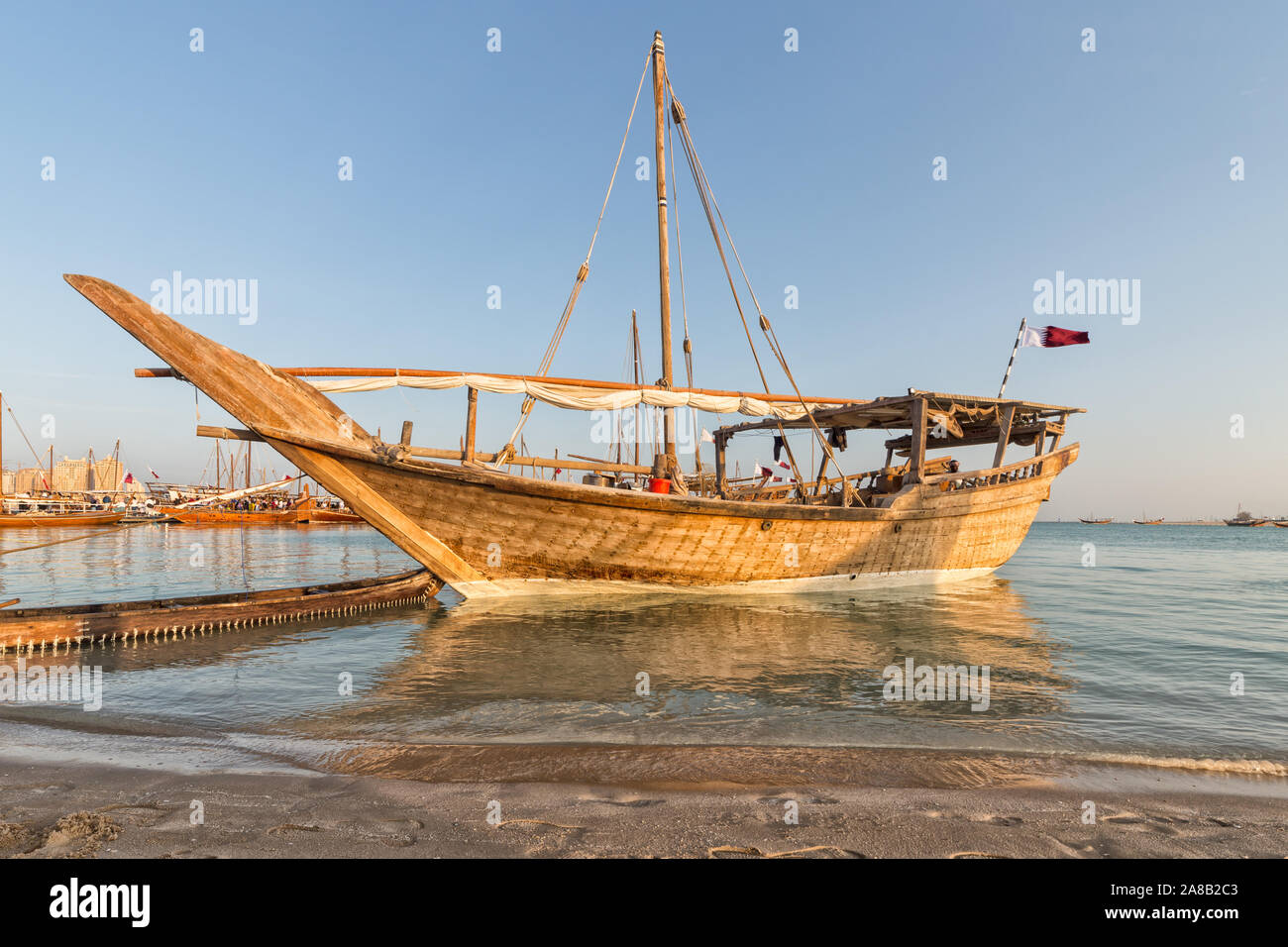Traditional wooden boat dhow in Arabic gulf with Qatari flag