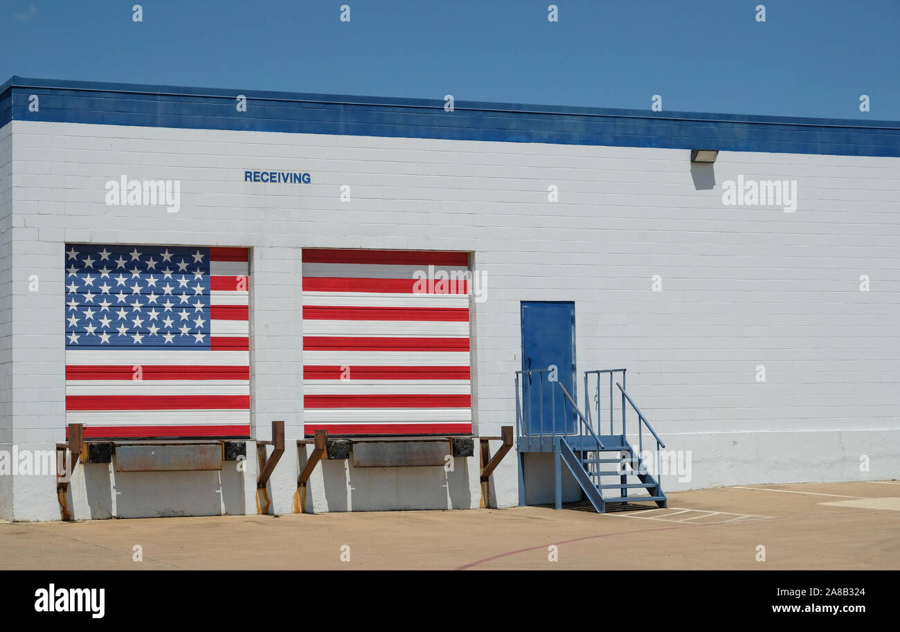 Warehouse with american flag painted receiving docks / Logistics building with entrance door and white and blue brick wall with copy space Stock Photo
