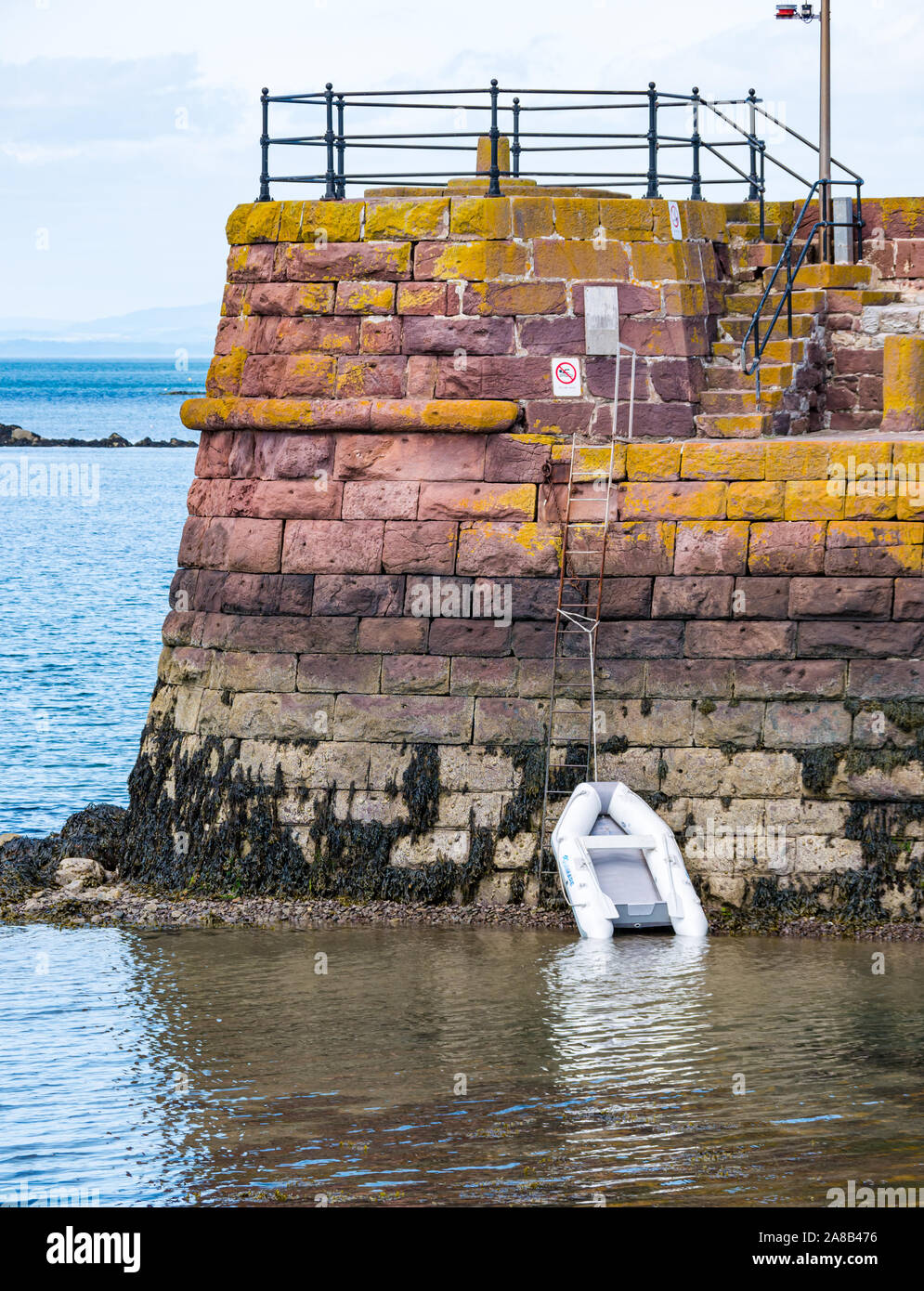 Harbour wall with dinghy attached by line, North Berwick, East Lothian, Scotland, UK Stock Photo