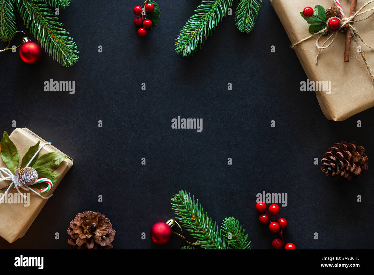 Holiday Christmas card background with festive decoration ball, stars, snowflakes, gift box, pine cones on a black background from Flat lay, top view. Stock Photo