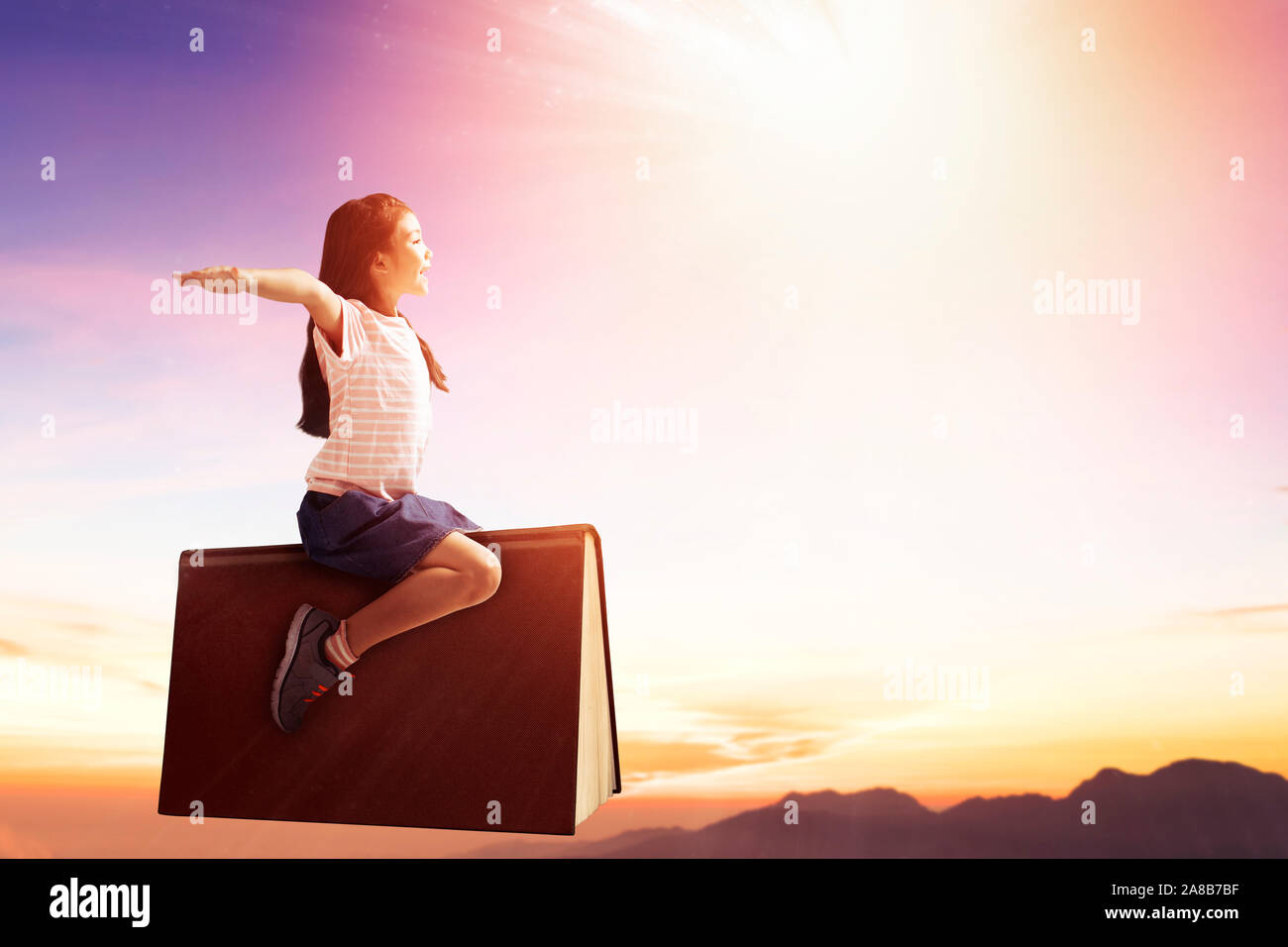happy little girl on book and flying in the sky Stock Photo - Alamy
