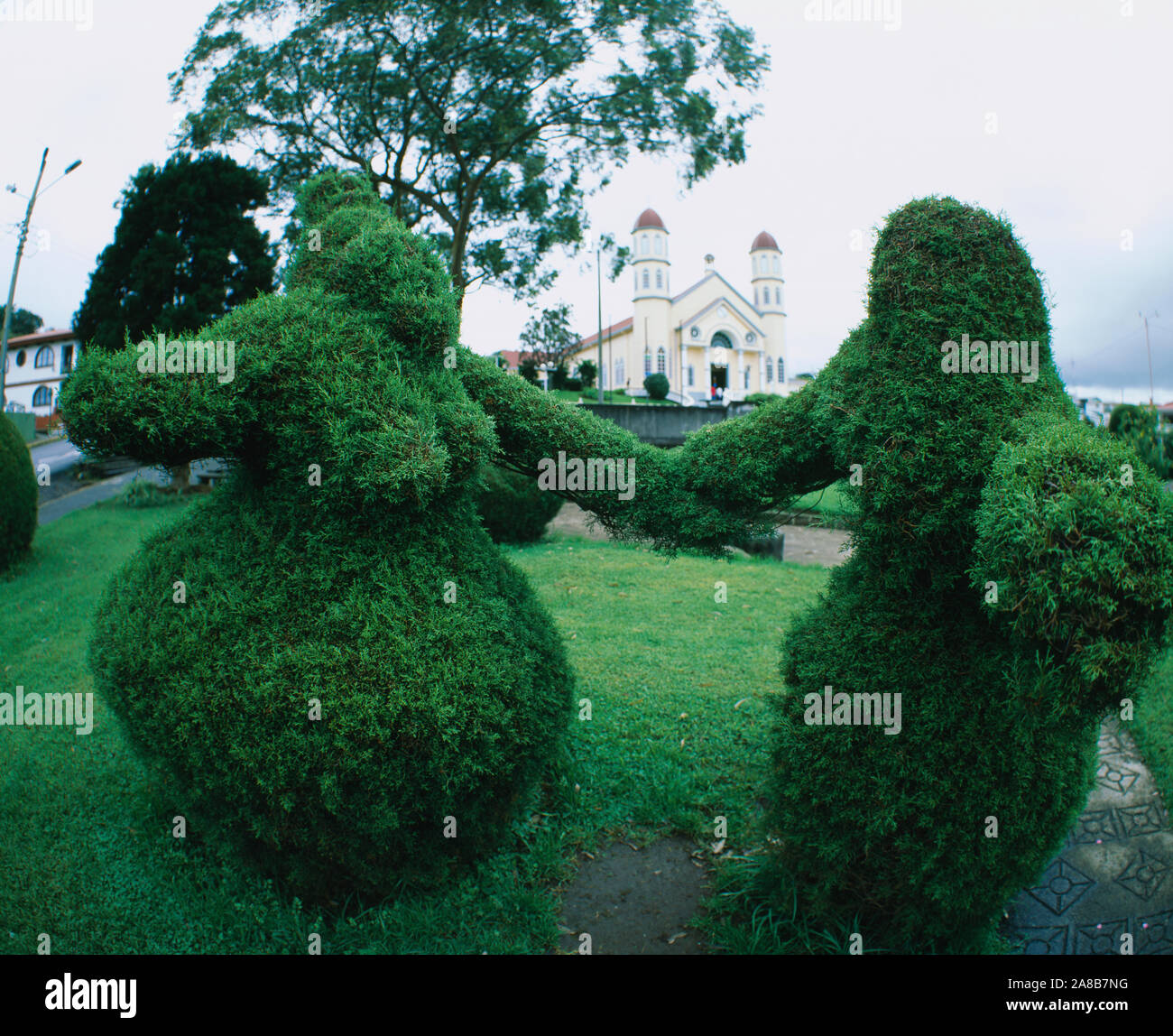 Topiary in a garden with a church in the background, Zarcero, Costa Rica Stock Photo