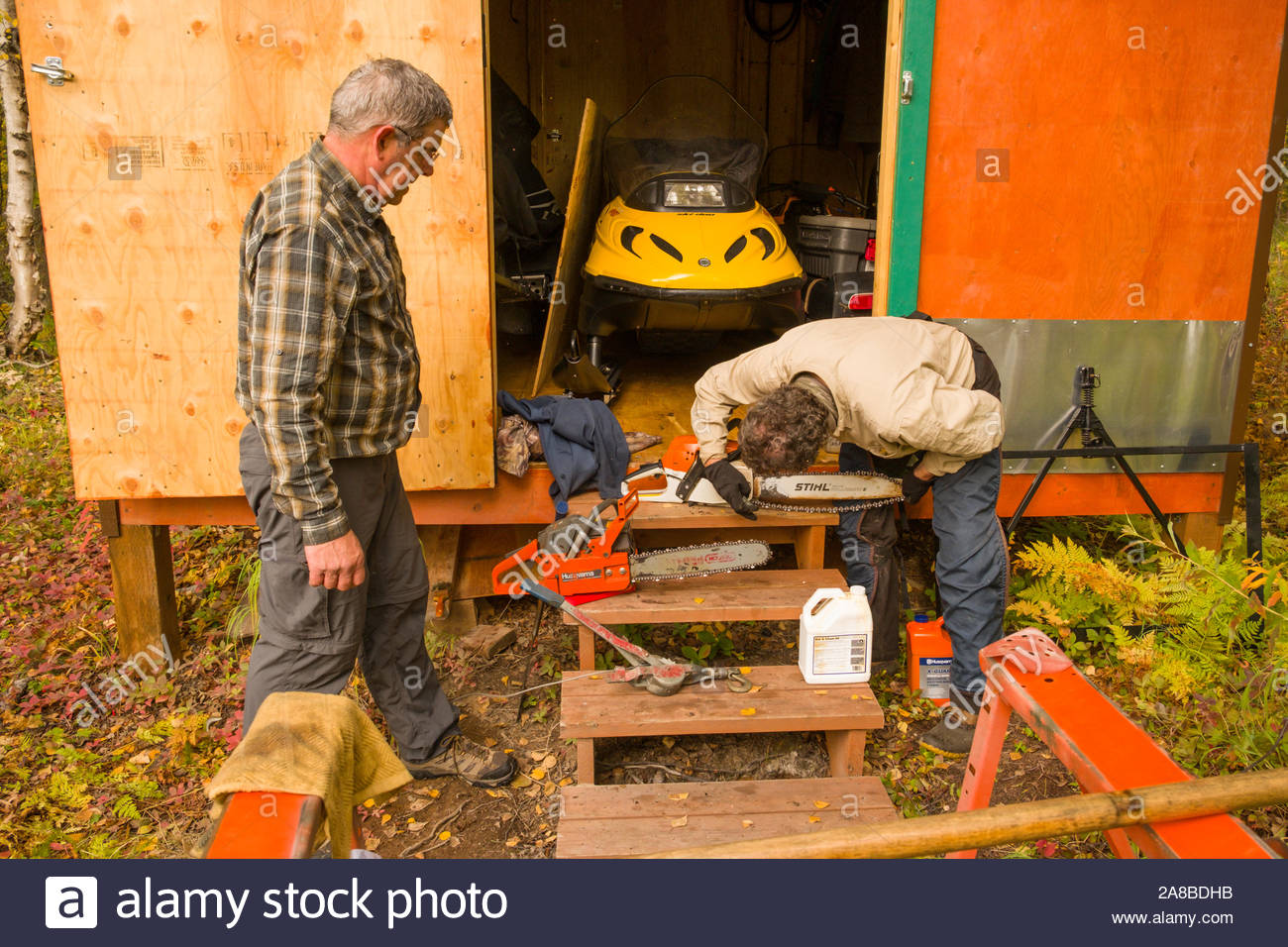 Man Adjusting And Maintaining His Gas Powered Chainsaw At A Remote