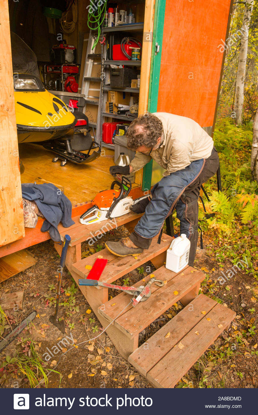 Man Adjusting And Maintaining His Gas Powered Chainsaw At A Remote