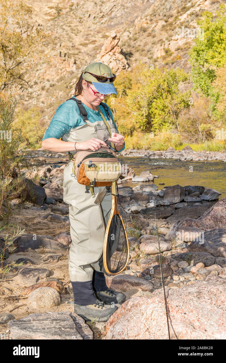 A woman prepares her fishing pole with line and a hook as she heads