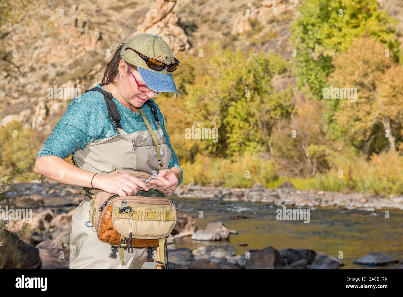 A woman prepares her fishing pole with line and a hook as she