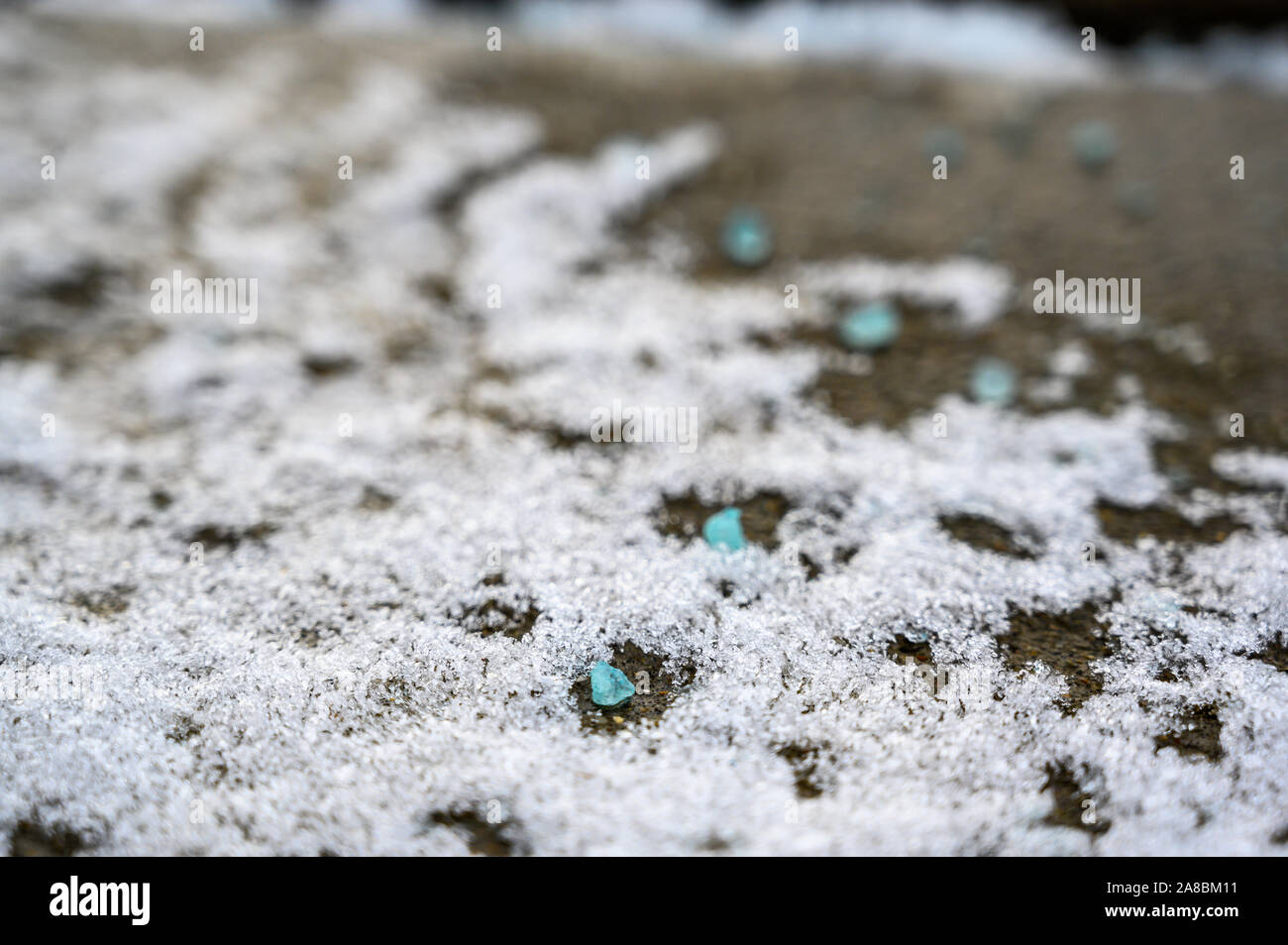 Ground level closeup view of rock salt icemelt on concrete with snow