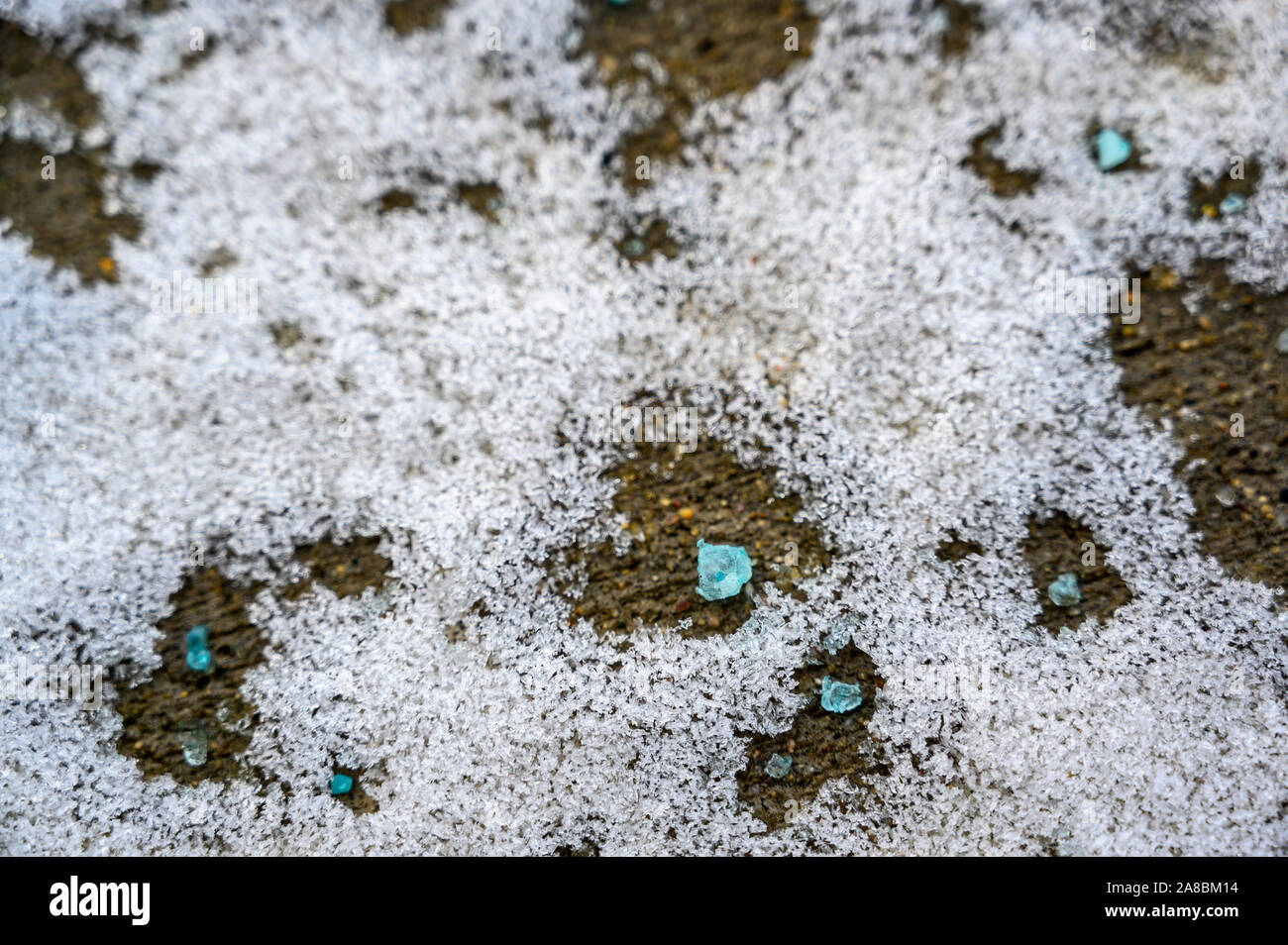 Ground level closeup view of rock salt icemelt on concrete with snow