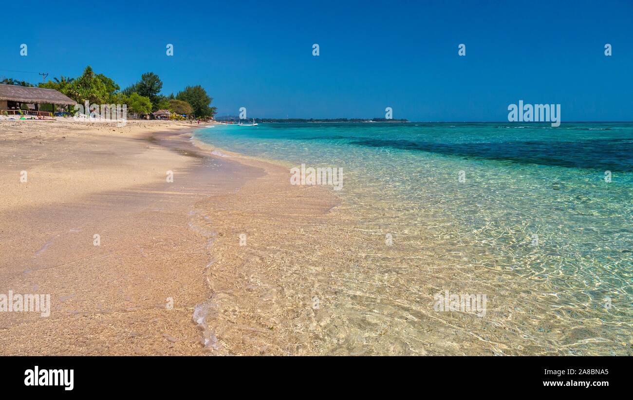 The sandy beach and crystal clear tropical sea water of Gili Air, one of the low-lying Gili Islands of Lombok Province, near Bali, Indonesia. Stock Photo