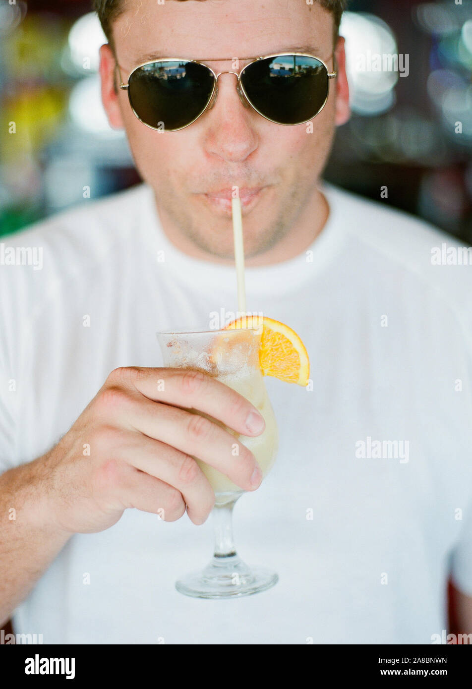 An adult male enjoying a painkiller cocktail at Pusser's Rum bar on Marina Cay while on holiday in the British Virgin Islands, Caribbean Stock Photo