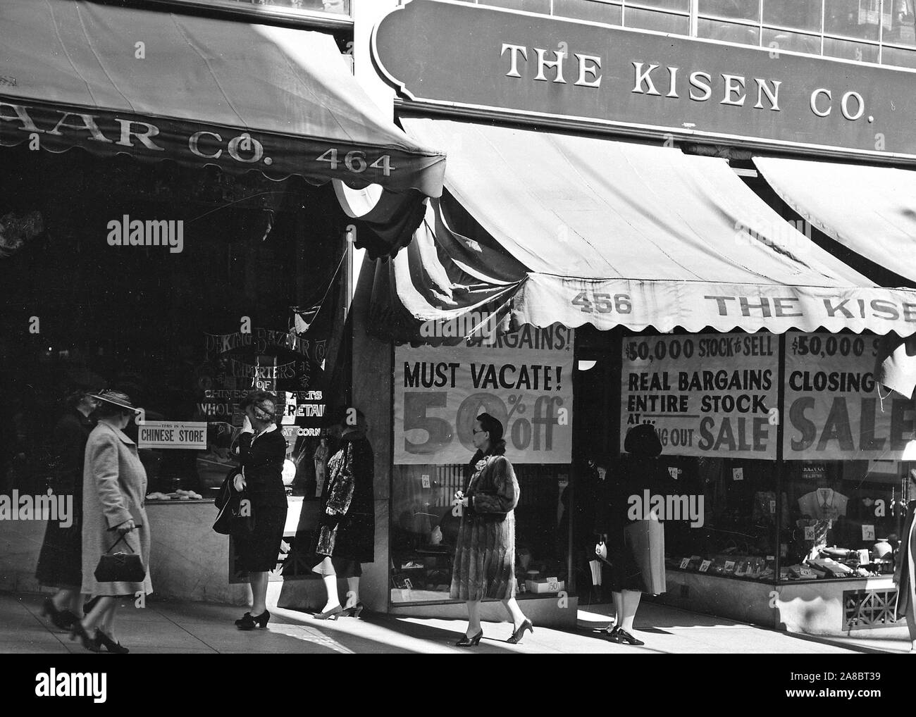 San Francisco, California. A study in contrast in Chinatown: The store on the right is operated by a proprietor of Japanese ancestry, and does a land office business as evacuation nears 4/4/1942 Stock Photo