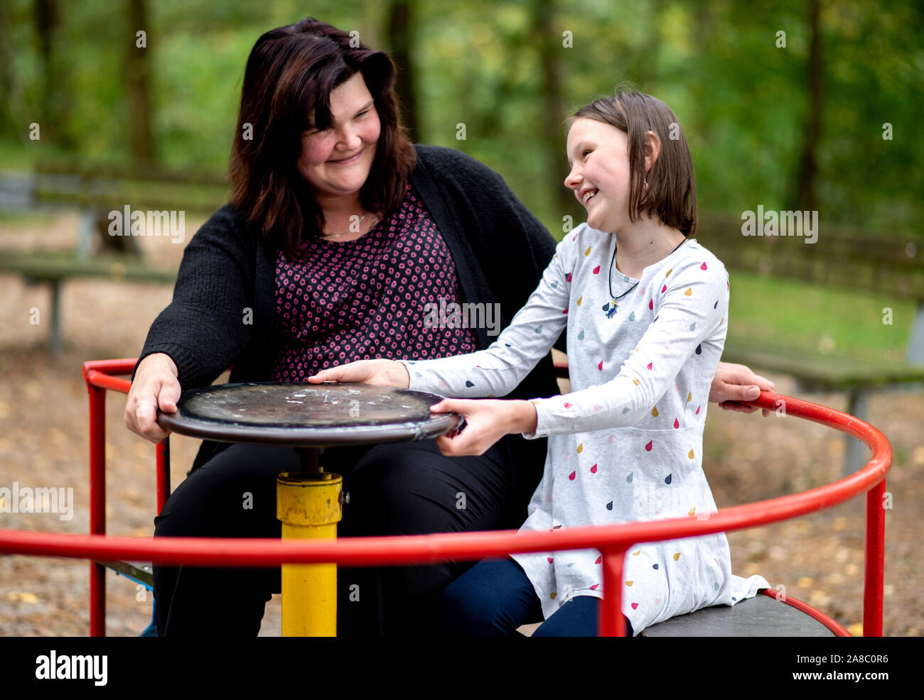 14 October 2019, Lower Saxony, Löningen: Kathrin Schenk and her daughter Tabea turn on a carousel in a playground. When her daughter Tabea starts blinking or the noise of her siblings suddenly becomes too much for her, Kathrin Schenk knows: 'A migraine attack is on the way. According to estimates by the German Migraine and Headache Society (DMKG), every tenth child has migraine. Photo: Hauke-Christian Dittrich/dpa Stock Photo