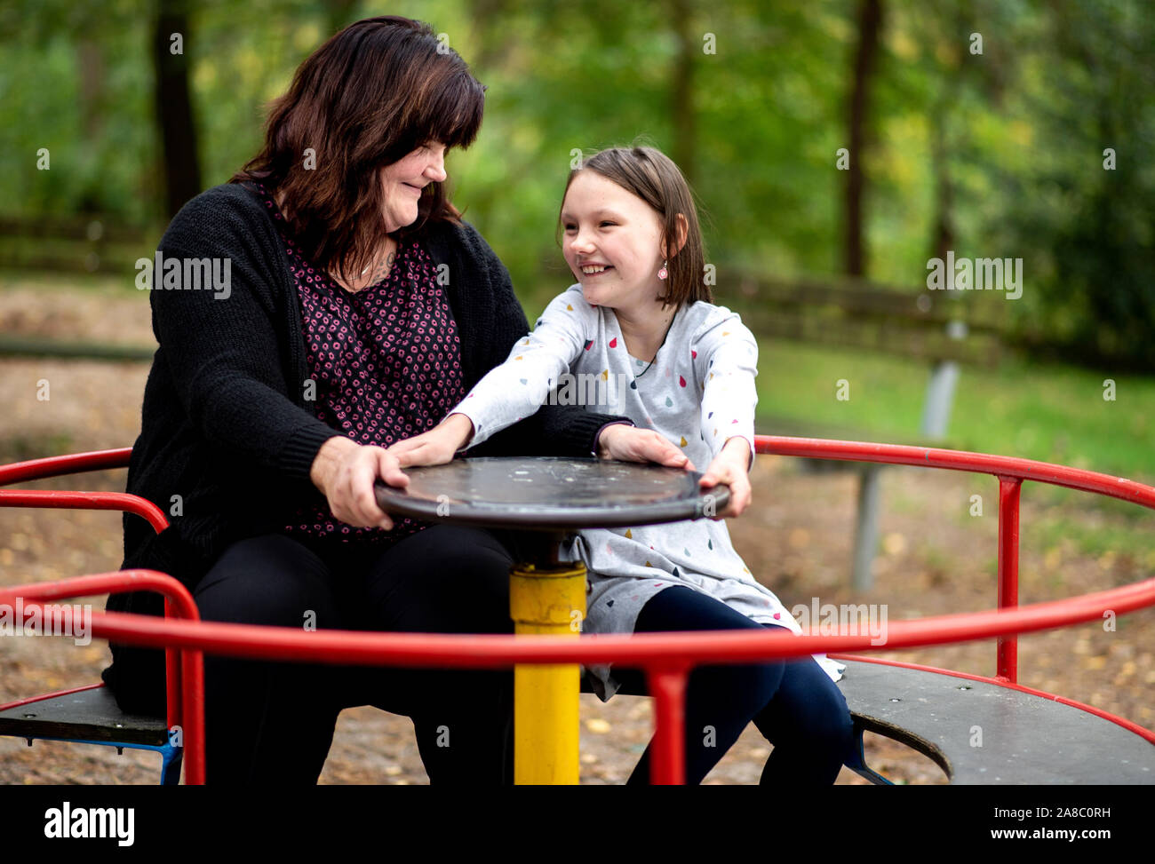14 October 2019, Lower Saxony, Löningen: Kathrin Schenk and her daughter Tabea turn on a carousel in a playground. When her daughter Tabea begins to blink or the noise of her siblings suddenly becomes too much for her, Kathrin Schenk knows: 'A migraine attack is on the way. According to estimates by the German Migraine and Headache Society (DMKG), every tenth child has migraine. Photo: Hauke-Christian Dittrich/dpa Stock Photo